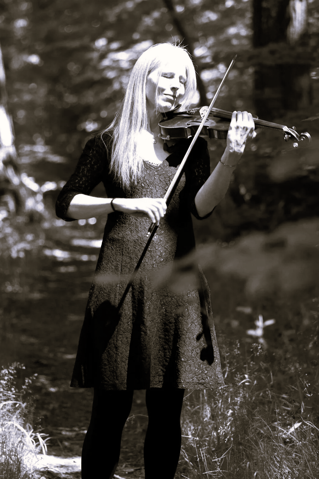 Dr. Nicole Besse (Bai Nike) with her violin in the forest.